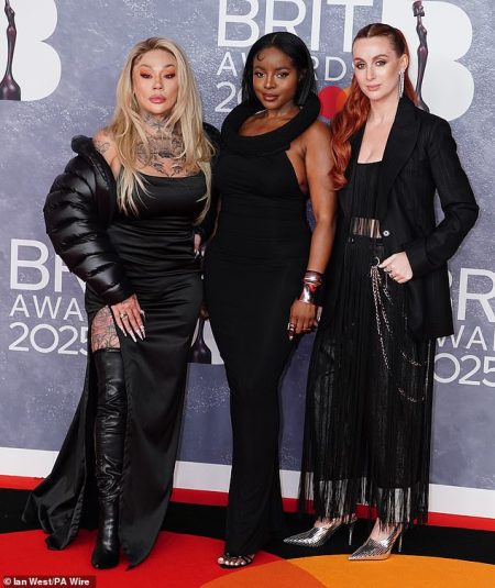 rewrite this title The Sugababes’ Mutya Buena puts on a VERY leggy display in a thigh-high split black gown as she coordinates with her bandmates at the BRIT Awards