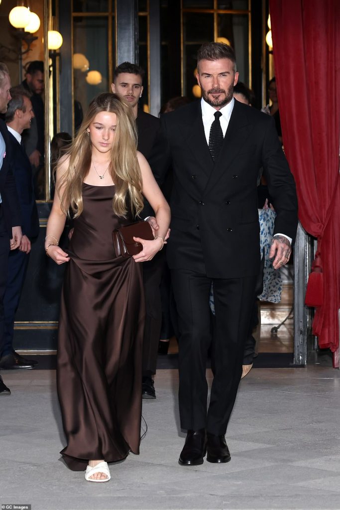 rewrite this title The Beckhams have arrived! Harper, 13, is her mother’s mini-me in a satin gown as she holds hands with father David while Romeo and Cruz step out with their girlfriends for Victoria’s Paris Fashion Week show